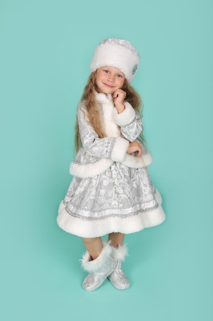 a little blonde girl with blue eyes in a New Years snow maiden costume on a blue background