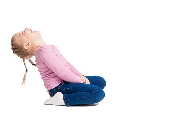 Little blonde girl with braids in jeans and a pink sweater laughs contagiously. Isolated.