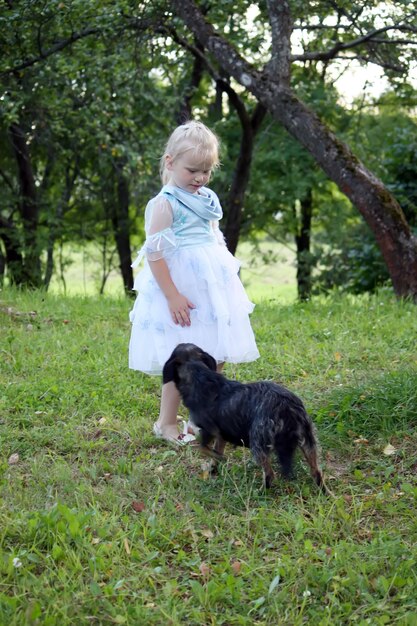 Маленькая блондинка с собакой в летнем саду