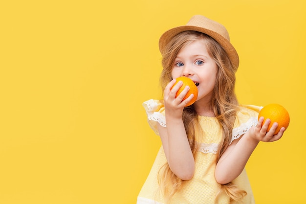 A little blonde girl with long hair with oranges in her hands