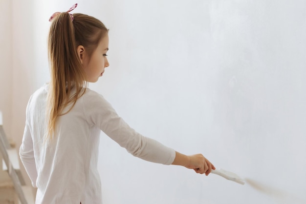 little blonde girl with wall paint roller during home renovation