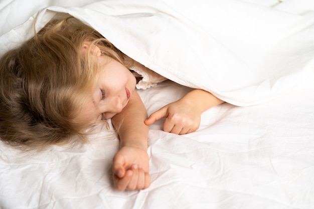 A little blonde is sleeping sweetly in a bed with white underwear. space for the text. healthy sleep of the child.