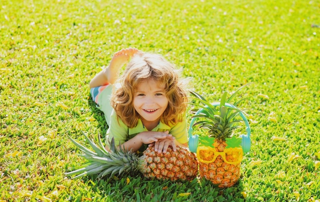 Little blonde kid hugging pineapple on nature background childhood healthy nutrition advertising clo