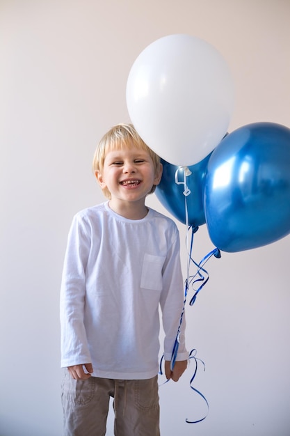 Photo little blonde smiling boy holding balloons celebration birthday