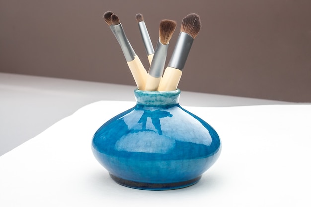 Photo little blue vase with makeup brushes