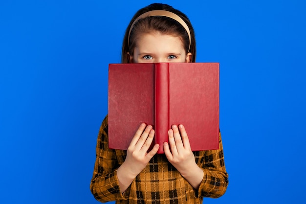 教科書の後ろに隠れる小さな本の読み手は嬉しそうな表情をしている