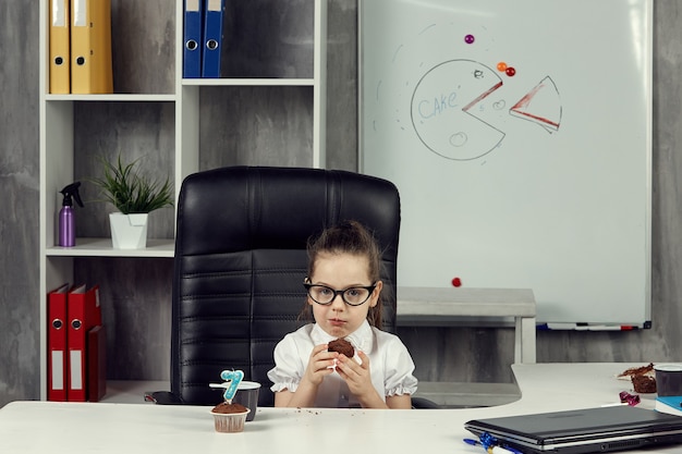 Foto il piccolo capo mangia un cupcake tra un lavoro e l'altro.