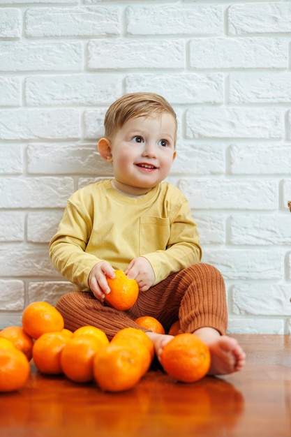 2歳の男の子がみかんを食べる子供は初めて柑橘系の果物に座りたい子供のための健康的な果物