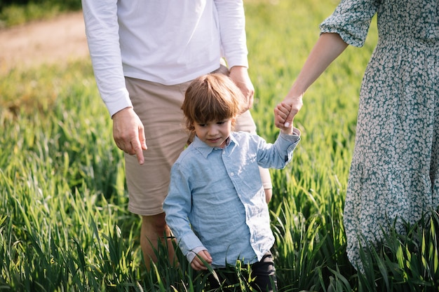 Little boy 3 years old spends time with parents in grass in the park, happy childhood concept