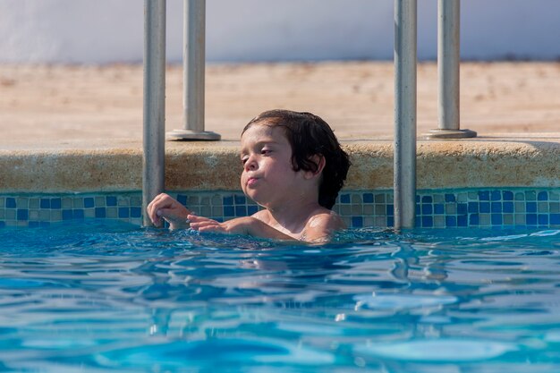 泳ぎ始める水の中のプールで楽しんでいる45歳の小さな男の子