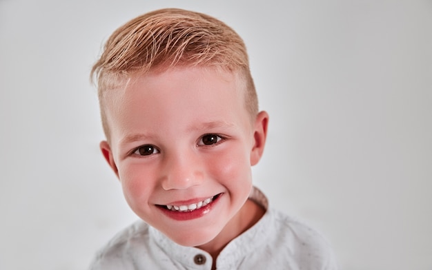 Il ragazzino di 5 anni in studio su sfondo grigio sta sorridendo