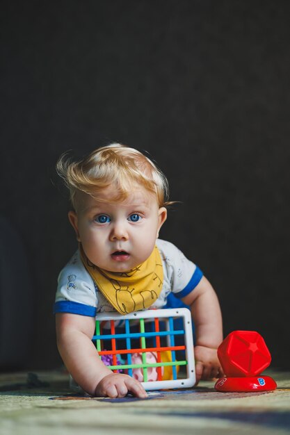 Foto un ragazzino di 6 mesi si siede su un tappetino di sviluppo e gioca con un sortitore con palle giochi educativi per bambini sviluppo della motilità delle mani nei bambini