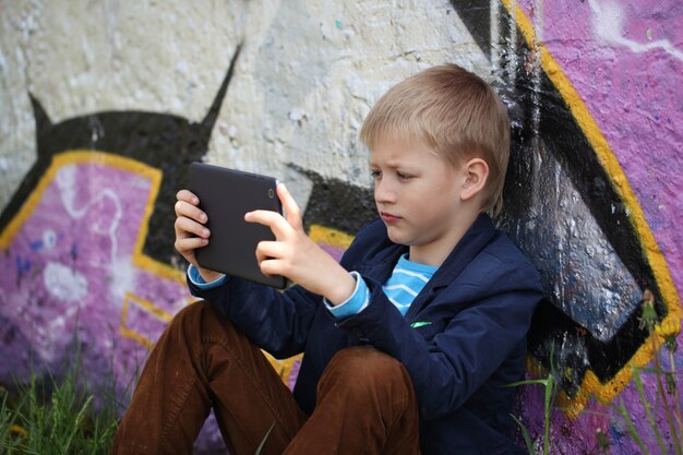 Little boy absorbed into his tablet for educating and playing.