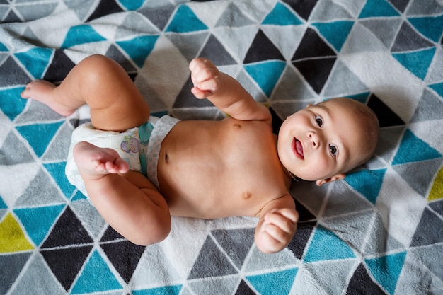 Little boy age 8 months and is smiling. He wears a diaper. Health and development of children