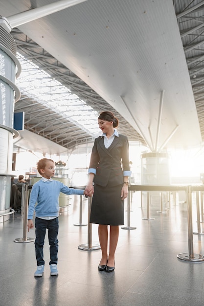 写真 空港で手を繋いでいる小さな男の子とスチュワーデス