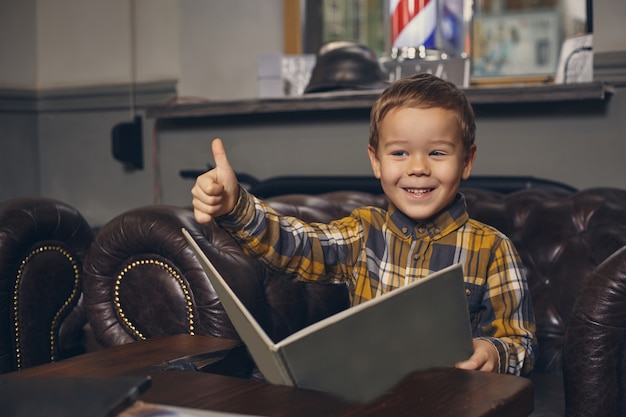 Little boy at the barbershop in waiting room waiting for master