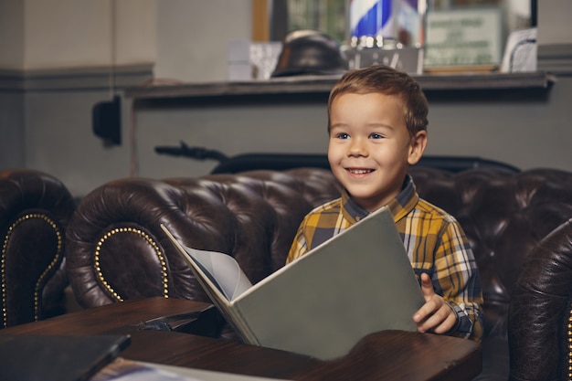 Little boy at the barbershop in waiting room waiting for master