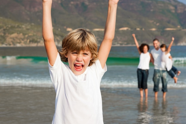 Little boy on a beach with his parents and his sister in background