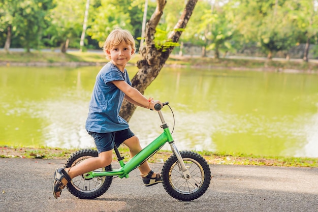자전거에 어린 소년입니다. 차도에서 움직임이 포착되었습니다. 미취학 아동의 자전거 첫 날. 움직임의 기쁨. 작은 운동 선수는 자전거를 타는 동안 균형을 유지하는 법을 배웁니다