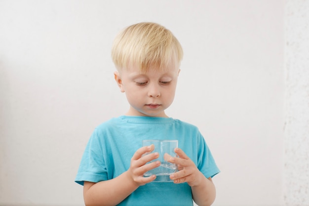 little boy in a blue Tshirt drinks water