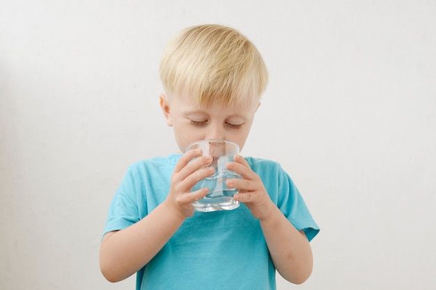 青いTシャツの小さな男の子は水を飲みます