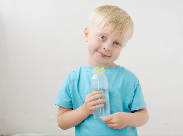 青いTシャツの小さな男の子は水を飲みます