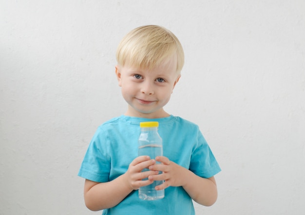 青いTシャツの小さな男の子は水を飲みます