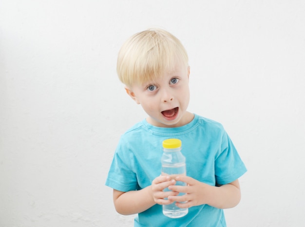 青いTシャツの小さな男の子は水を飲みます