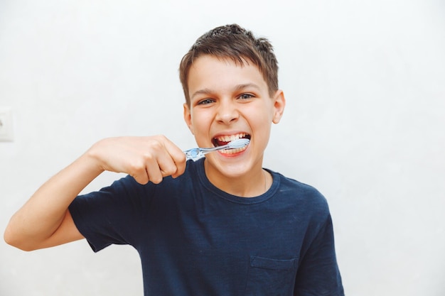 A little boy brushes his teeth on a white background the boy is holding a green apple and brushing his teeth dentistry and medicine