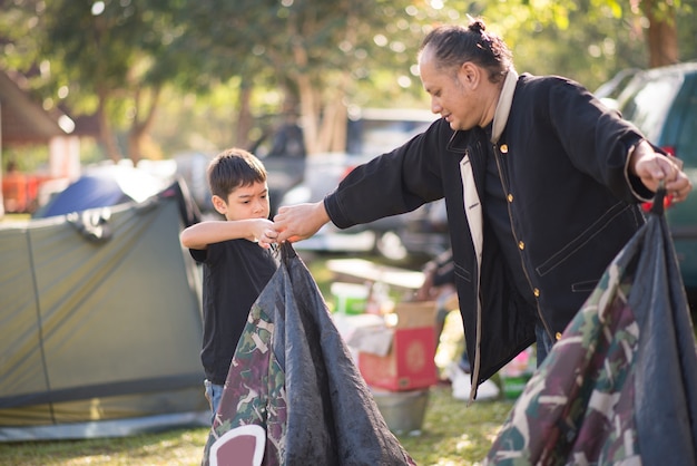 家族の休日の夏の時間とキャンプのためのテントを構築する小さな男の子