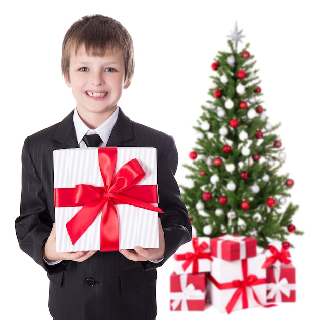 Little boy in business suit with gift box and christmas tree isolated on white background