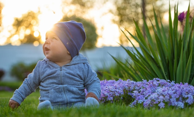 Little boy in a cap is sitting on the lawn