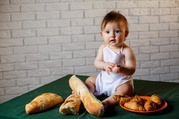 Little boy in a cap and with bread. Little child dressed as a cook in the kitchen.