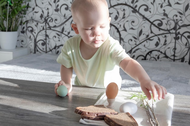 小さな男の子がイースターを祝う木製のテーブルに座って食べる