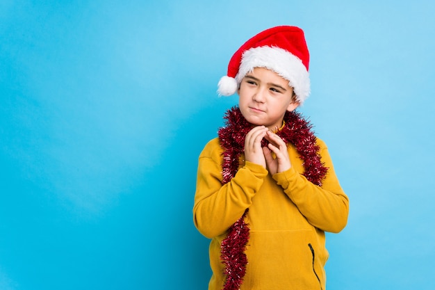 Little boy celebrating christmas day wearing a santa hat isolated making up plan in mind, setting up an idea.