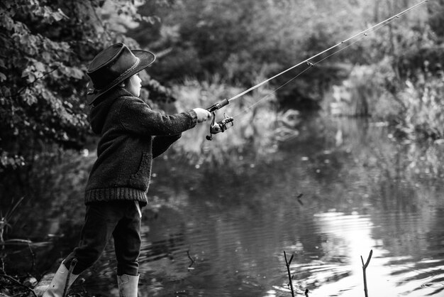 Little boy child catching a fish Kid with fishing rod at lake Lonely happy little boy fishing from beach lake