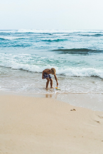 Little boy child playing on the beach by the ocean.