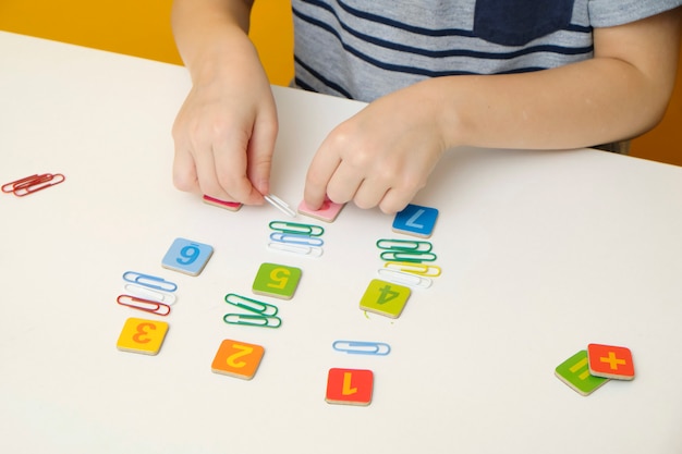 Little boy child preparing for elementary school doing simple math exercises. Close up