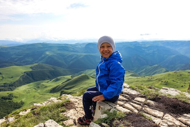 A little boy on the cliff of the plateau against the background of Mount Elbrus Bermamyt