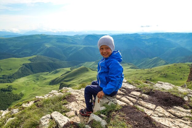 A little boy on the cliff of the plateau against the background of Mount Elbrus Bermamyt