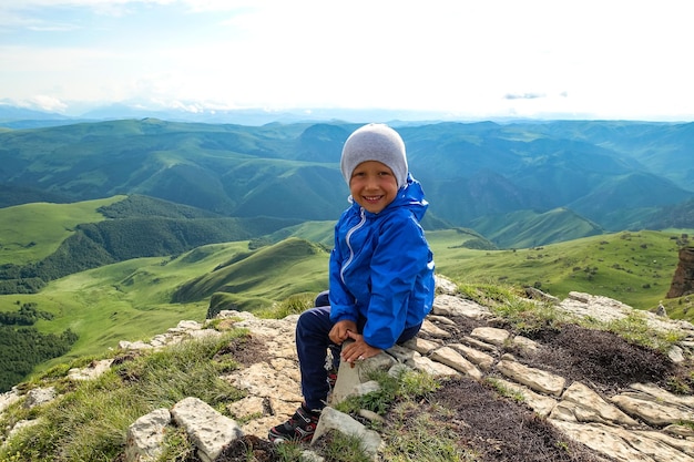 A little boy on the cliff of the plateau against the background of Mount Elbrus Bermamyt