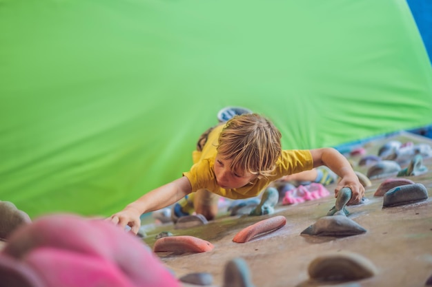 Little boy climbing a rock wall in special boots indoor