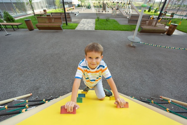 A little boy climbs a climbing wall on a modern playground