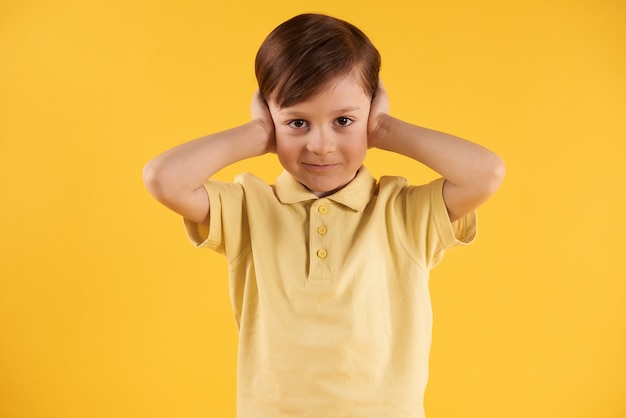 Little boy closes ears with hands.