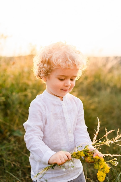 Little boy collects herbs in the field