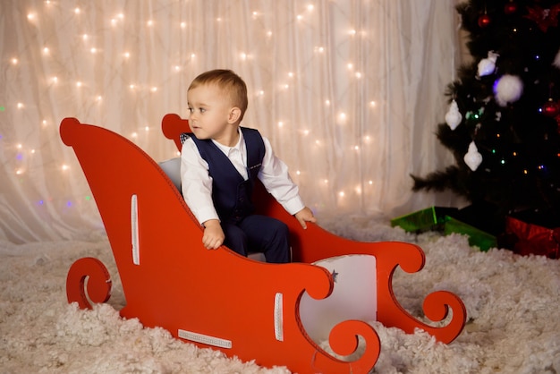 Little boy in a costume waiting for a Christmas near the christmas tree