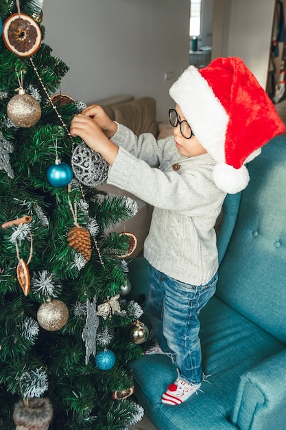 小さな男の子がクリスマスツリーを飾る