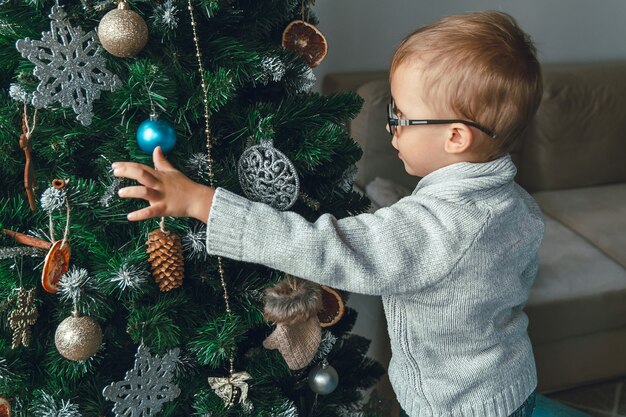 小さな男の子がクリスマスツリーを飾る