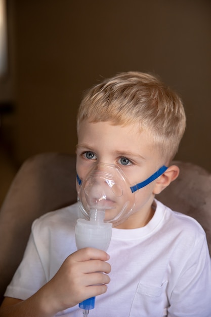 A little boy does inhalations with a nebulizer at home he is sick Help at home with cough asthma