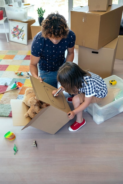 Little boy drawing in a moving box with his father